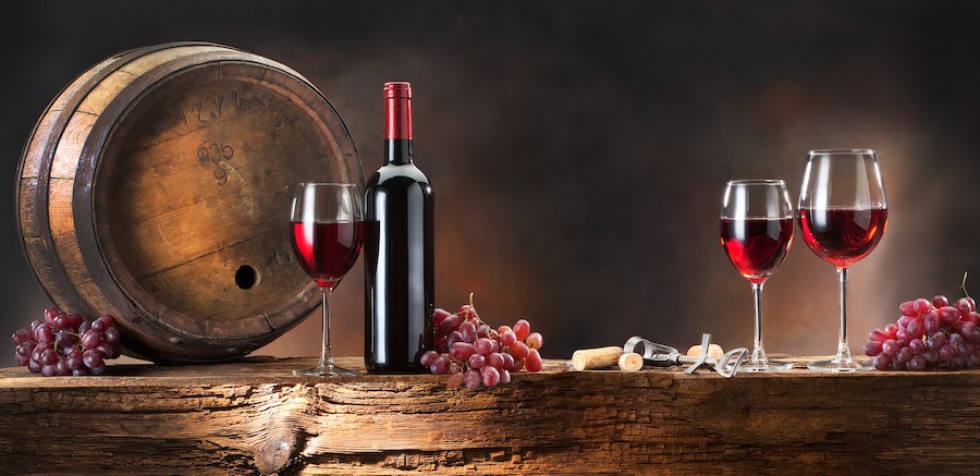 still life with red wine with barrel on old wood