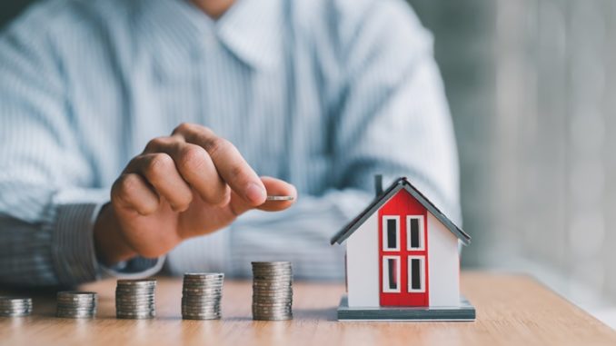 stack of money and home models, home insurance ideas and insurance agents for those interested.
